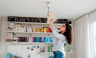 Nainen vaihtaa lamppua valoon