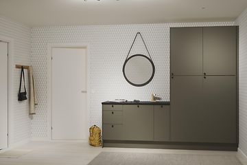 Epoq Trend Moss Green -sarjan kaapeilla varustettu kodinhoitohuone, musta työtaso, jonka ylle on ripustettu pyöreä peili