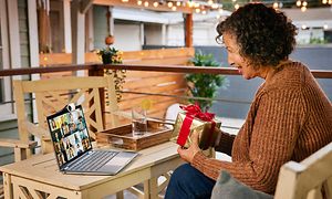 Google - Chromebook - lahjaa kädessään pitävä nainen puhuu etäyhteydellä HP X360 Chromebookin kautta