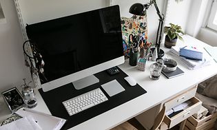 Kotitoimisto jossa mac, hiiri ja näppäimistö pöydällä