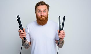 Mies suoristusrauta ja kiharrin käsissään