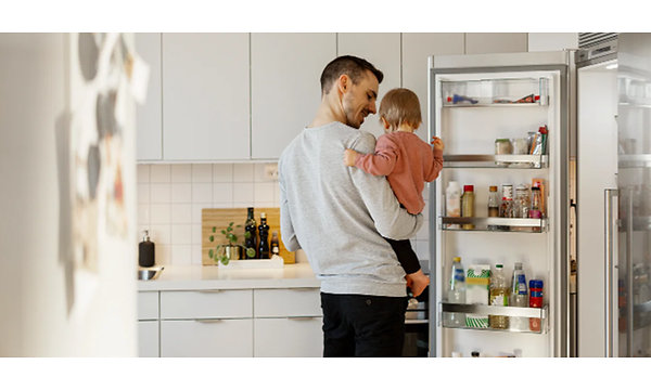 Mies vauva sylissään jääkaapilla