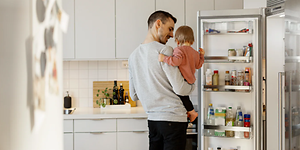 Mies vauva sylissään jääkaapilla