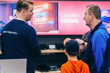 Myyjä opastaa asiakkaita Lenovo tablettien äärellä myymälässä