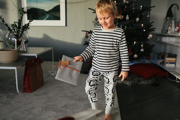 Joululahjat lapsille - Pieni poika pitelee joululahjaa kädessään