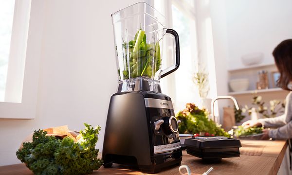 Täynnä kasviksia oleva VitaBoost High Speed Blender- tehosekoitin keittiön työtasolla