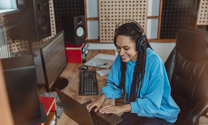 Nainen miksaa musiikkia kuulokkeet korvillaan