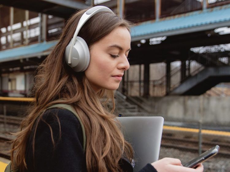 Nainen on-ear kuulokkeiden kanssa kävelee juna-asemalla