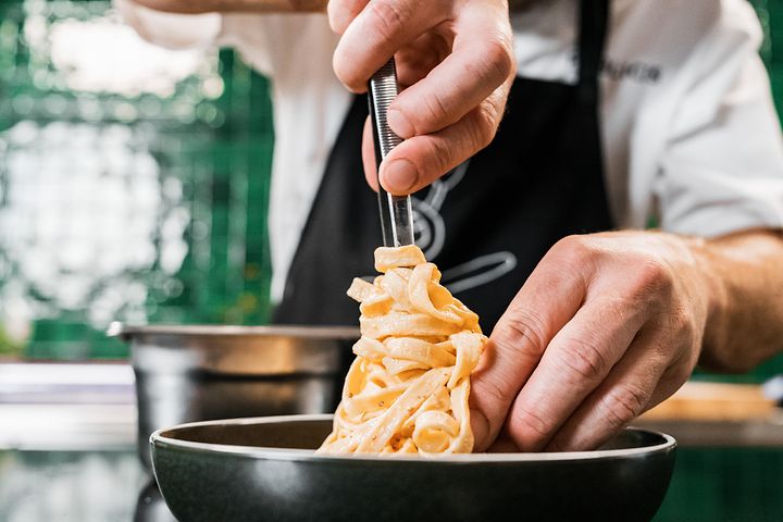 Kokki asettaa pastaa lautaselle