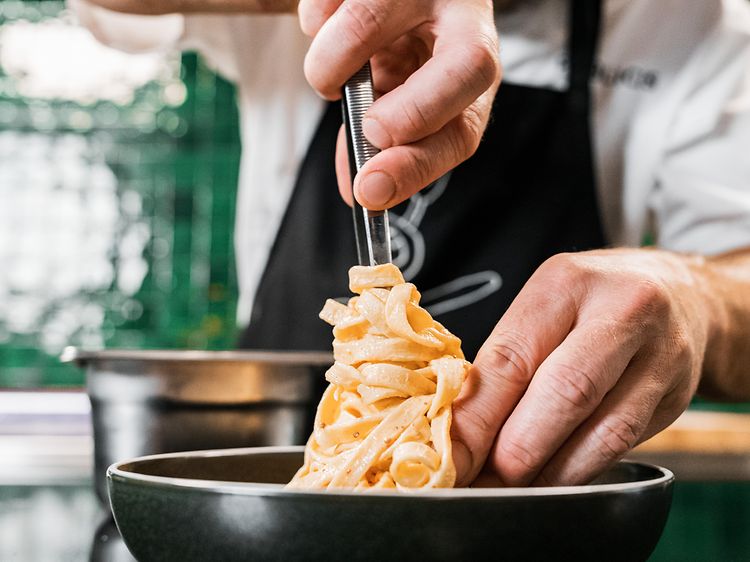 Kokki asettaa pastaa lautaselle