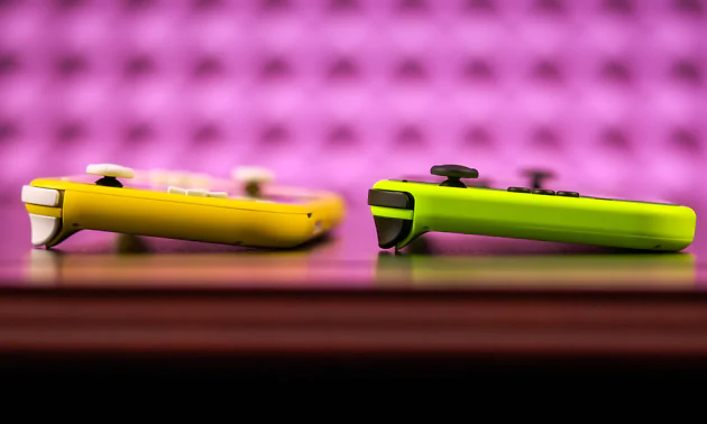 Keltainen ja vihreä Nintendo Switch Lite -konsoli pöydällä violettia taustaa vasten