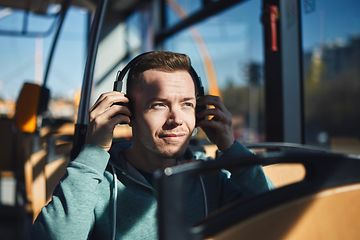 Mies bussissa laittaa kuulokkeita korvilleen