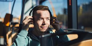 Mies bussissa laittaa kuulokkeita korvilleen