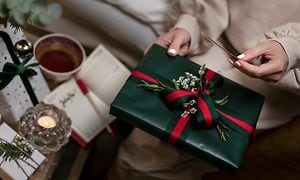 Joulu - Nainen pitelee joululahjaa ja joulukorttia