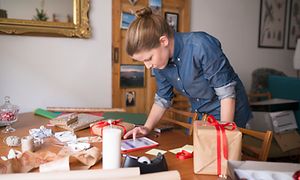 Joulu - Nainen paketoi joululahjoja iPadiä silmäillen