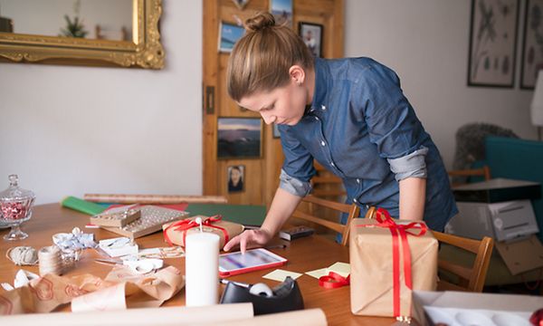 Joulu - Nainen paketoi joululahjoja iPadiä silmäillen