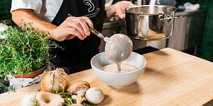 Kokki kaataa kasviskeittoa kulhoon