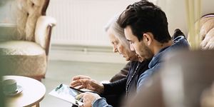 Mies ja vanha nainen käyttävät yhdessä tablettia