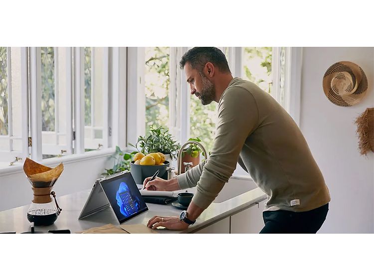 Keittiösaarekeella työskentelevä mies sekä taitettuna oleva HP EliteBook