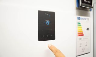 Miehen sormi osoittaa pakastimen digitaalista lämpötilasäädintä