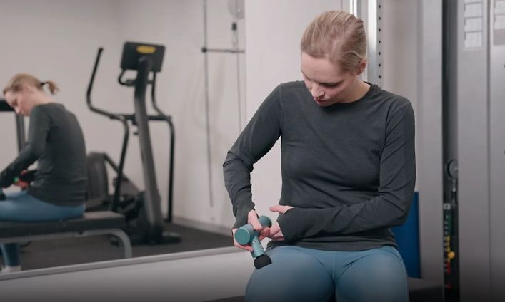 Kuvakaappaus hierontavasaran käytöstä kertovasta videosta, jossa nainen käyttää laitetta reitensä hieromiseen