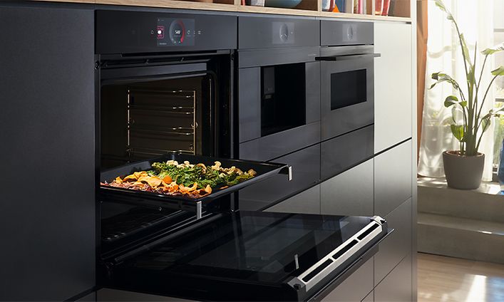 Bosch accent line -uuni luukku raollaan ja uunipellillinen kasviksia