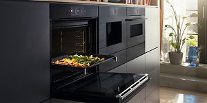 Bosch accent line -uuni luukku raollaan ja uunipellillinen kasviksia