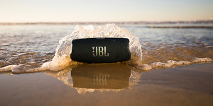 JBL Charge 5 -kaiutin rannalla, jossa aallot lyövät kaiutinta vasten
