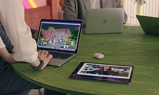 Apple Business Manager - vihreällä pöydällä esillä MacBook-tietokoneita, iPadeja ja Airpodeja