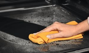 Pyrolyysipuhdistus-toiminto ja käsi pyyhkimässä Electrolux-höyryuunin sisältä