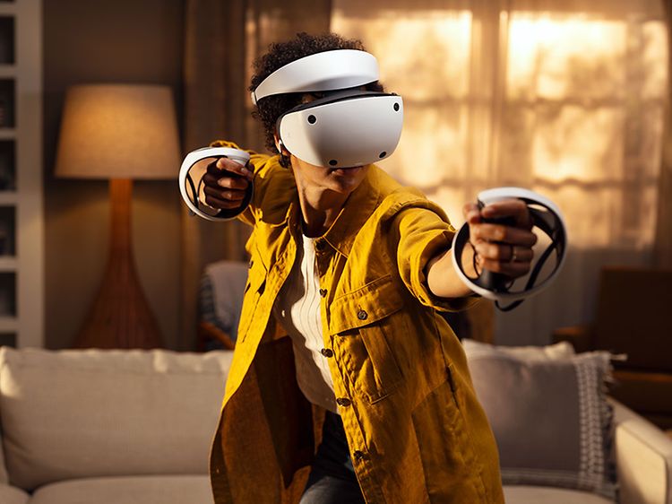 Henkilö tutustuu VR-pelimaailmoihin olohuoneessaan Playstation VR2:n avulla
