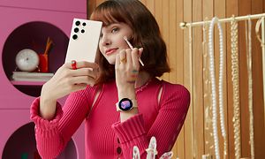 Nainen pitelee Galaxy S23 Ultra 5G -puhelinta kädessään samalla kun hän meikkaa itseään