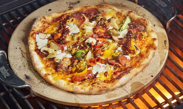 Grillin grilliritilän päällä pizza paistumassa pizzakivi allaan