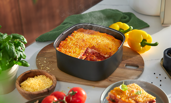 Philips Airfryer XXL -kiertoilmakypsentimen paistoalustalla lasagnea ja tuoreita kasviksia sen ympärillä