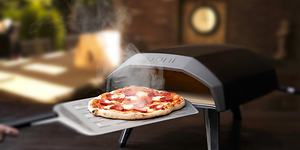 Ooni Koda -pizzauuni ja vastapaistettu pizza pizzalastan päällä