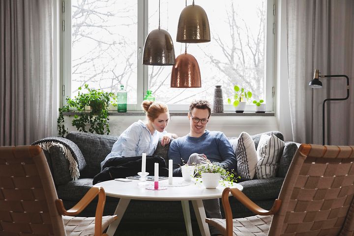 Sohvalla istuva pariskunta katsoo yhdessä puhelinta