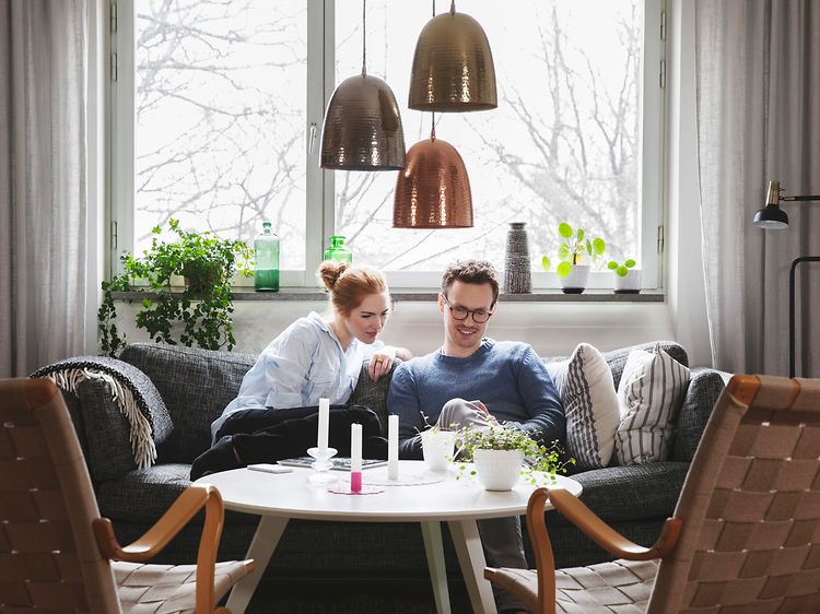 Sohvalla istuva pariskunta katsoo yhdessä puhelinta