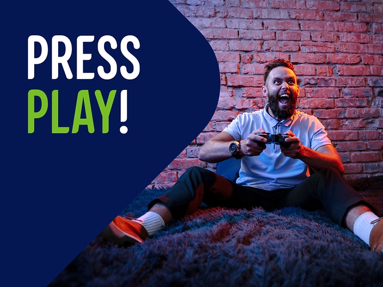 Mainoskuvassa mies istuu pelaamassa konsolia lattialla ja teksti "Press play"
