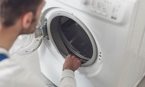 Mies tarkistaa pyykinpesukoneen kumilistoja