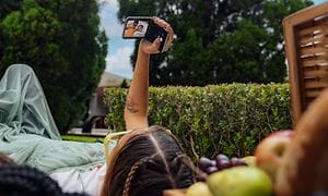 Ystävänsä kanssa nurmella makaava tyttö ottaa selfietä Motorola Razr -puhelimella