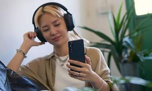 Kuulokkeet päässä oleva nuori tyttö kuuntelee musiikkia Xperia 1 V -älypuhelimella