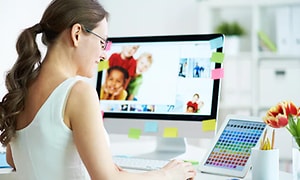 Nainen muokkaa kuvia tietokoneen näytöllä