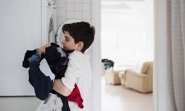 Poika tyhjentää pyykkiä pyykinpesukoneesta
