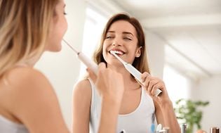 Teaser-kuva tytöstä, joka pesee hampaitaan sähköhammasharjalla