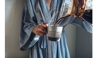 Nainen kaataa kahvia kahvikuppiin