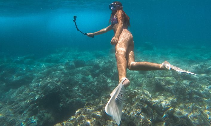 Nainen snorklaa ja kuvaa veden alla GoPro HERO12 Black -actionkameralla