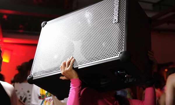 Nainen kuljee tanssilattian läpi kantaen Soundboks 4 -kaiutinta hartiallaan