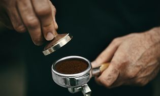 ME-Time - omaa aikaan - Mies painaa vastajauhettua espressokahvia portafilteriin ennen tuoreen kahvin keittämistä