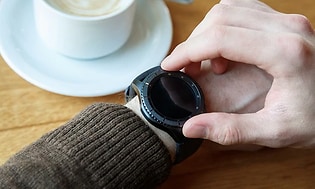 Person checking smart watch whilst drinking coffee