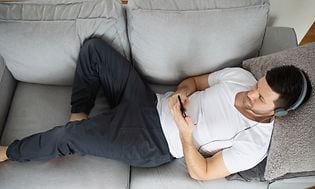 ME-Time - omaa aikaa - Kuulokkeet päässä oleva mies makaa sohvalla ja kuuntelee musiikkia